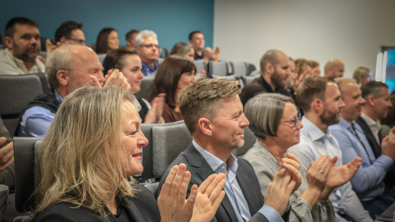 Folk som sitter i en sal og applauderer 